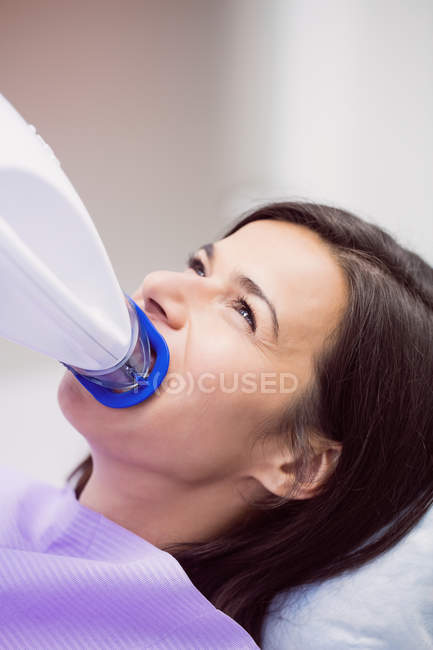 Paciente do sexo feminino recebendo tratamento com luz dentária na clínica odontológica — Fotografia de Stock