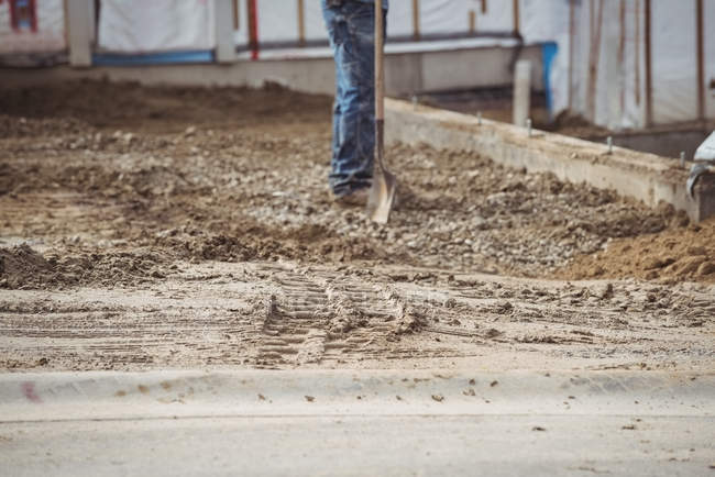 Low section of construction worker levelling mud at construction site — Stock Photo