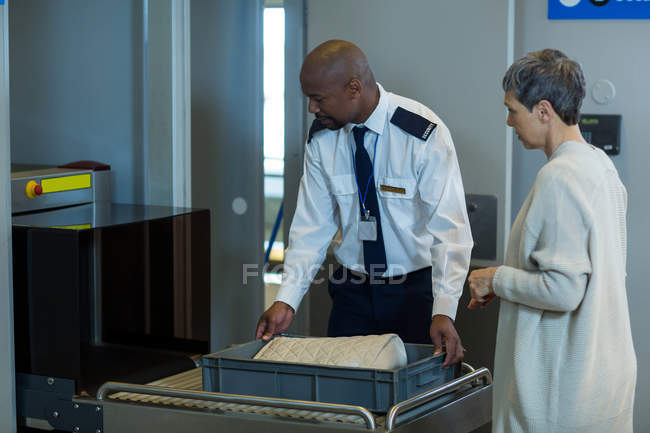 Airport security officer checking a bag of commuter in airport terminal — Stock Photo