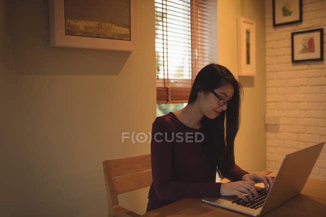 Mulher usando laptop na mesa na sala de estar em casa — Fotografia de Stock