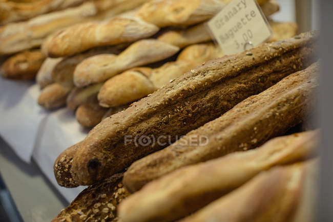 Various types of bread stacked together at bakery counter in supermarket — Stock Photo