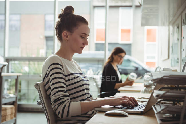 Female business executive using laptop in office — Stock Photo