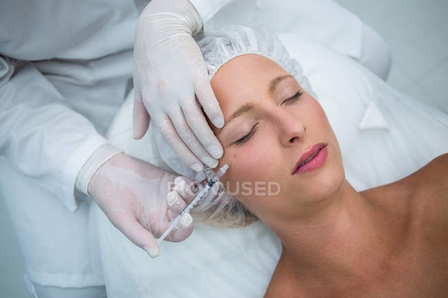 Крупный план средней взрослой пациентки, получающей инъекцию ботокса на лицо — стоковое фото