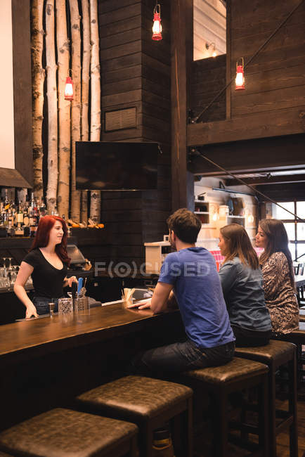 Бармен взаємодія з клієнтами за барною стійкою — стокове фото