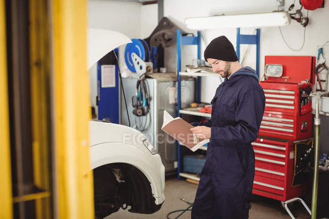 Mechaniker lesen Bedienungsanleitung in Reparaturwerkstatt — Stockfoto