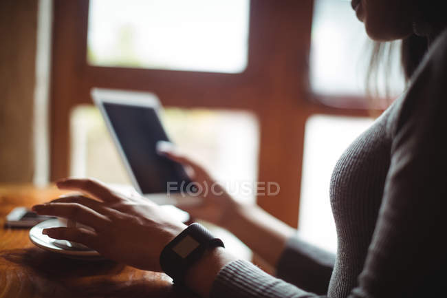 Frau benutzt digitales Tablet bei einer Tasse Kaffee im Café — Stockfoto