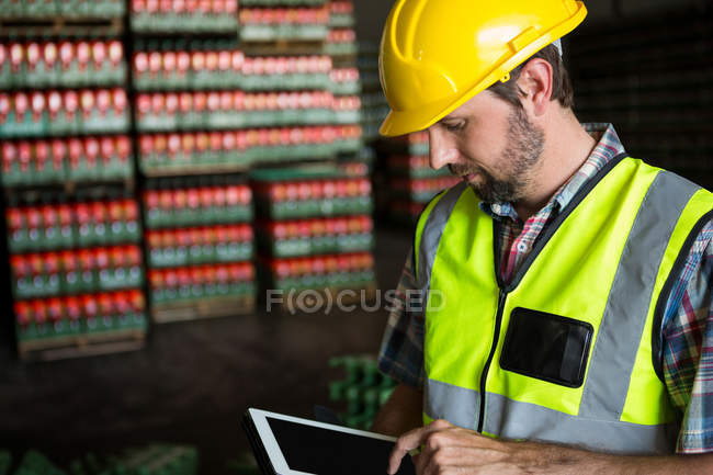 Jeune homme utilisant une tablette numérique dans un entrepôt — Photo de stock