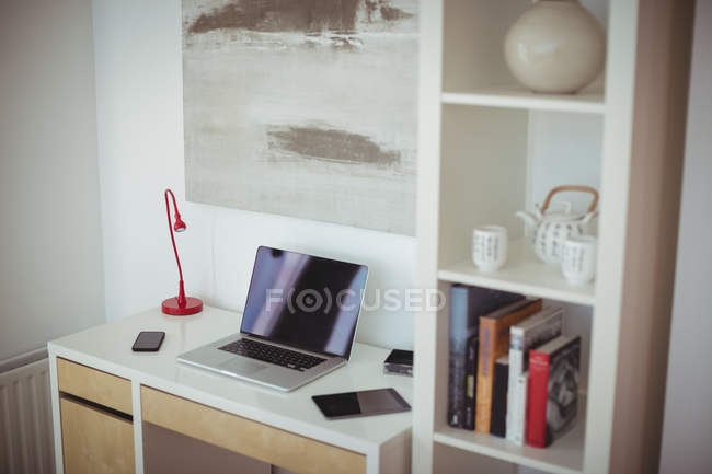 Ordenador portátil, tableta digital y teléfono móvil se mantienen en la mesa en la sala de estudio en casa - foto de stock