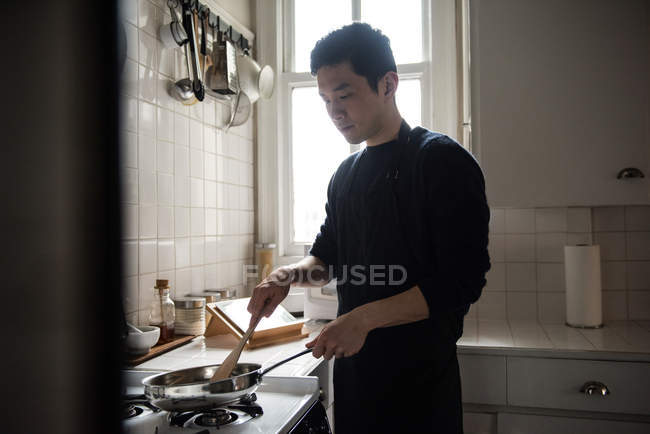 Человек готовит еду на кухне дома — стоковое фото