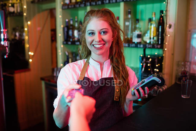 Cliente haciendo el pago a través de tarjeta de crédito en el mostrador en bar - foto de stock