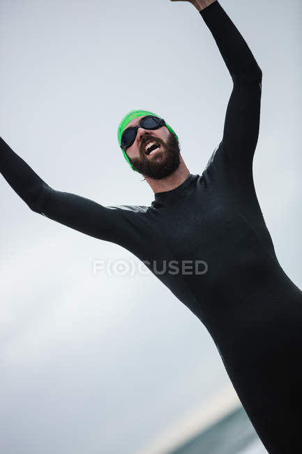 Крупный план спортсмена кричащего на пляже с поднятыми руками — стоковое фото