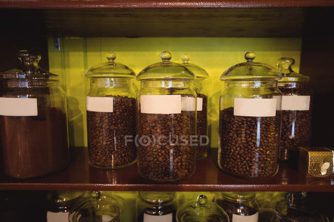 Gros plan des pots de grains de café disposés sur l'étagère dans le magasin — Photo de stock