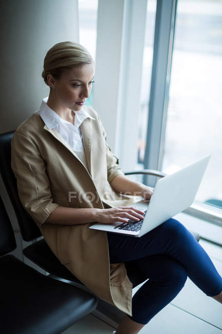 Beautiful woman using laptop in waiting area at airport terminal — Stock Photo