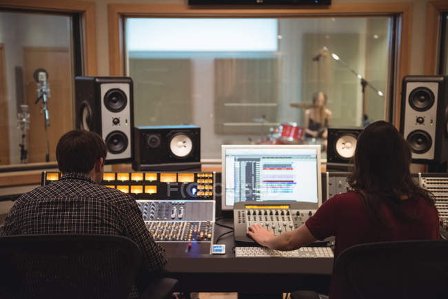 Rear view of audio engineers using sound mixer in recording studio — Stock Photo