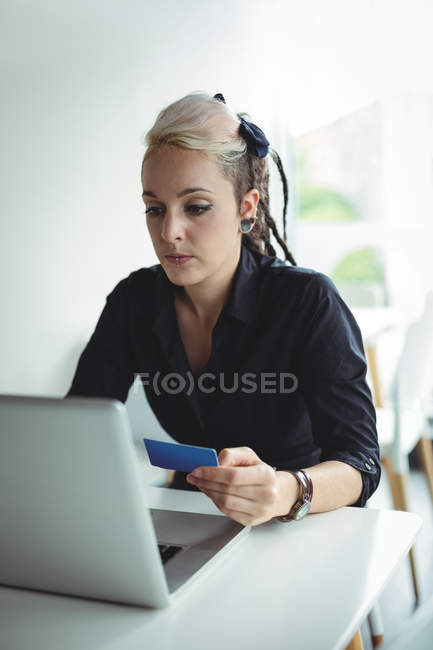 Mulher fazendo o pagamento on-line usando laptop e cartão de crédito no café — Fotografia de Stock