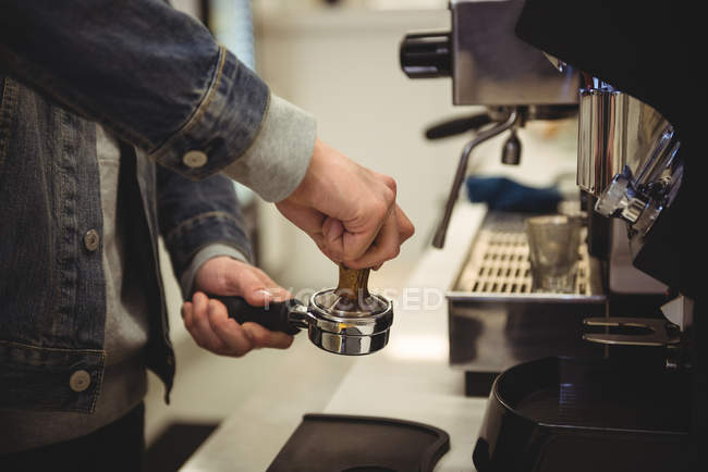 Mid-section of man pressing coffee with tamper in portafilter — Stock Photo