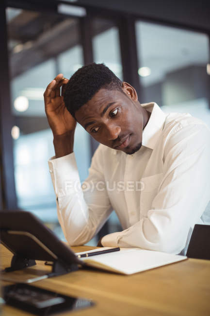 Thoughtful businessman working over digital tablet in office — Stock Photo