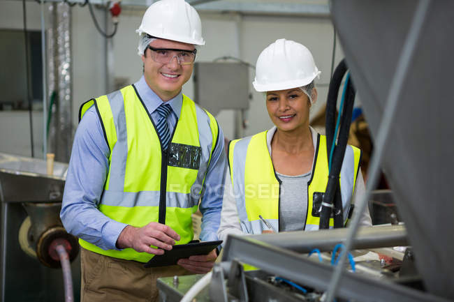 Retrato de técnicos sorridentes examinando a máquina na fábrica — Fotografia de Stock