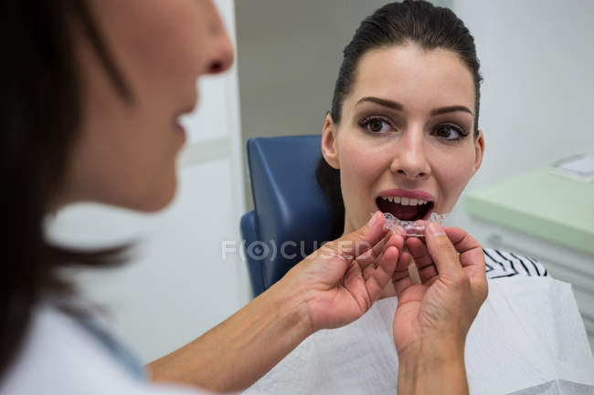 Dentist assisting patient wearing orthodontic silicone invisible braces — Stock Photo