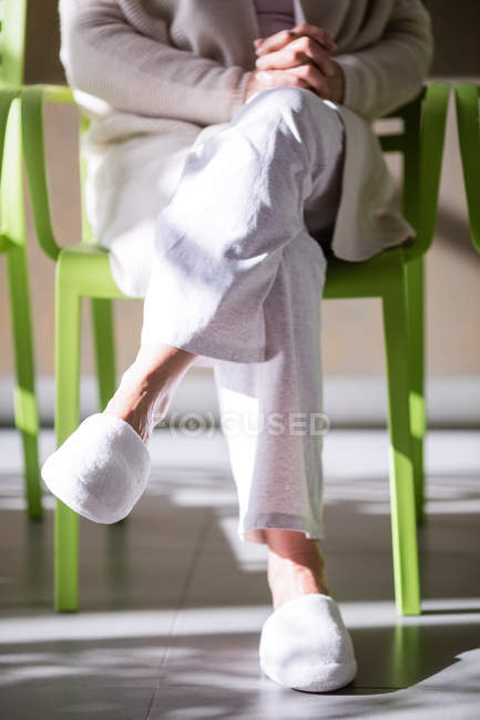 Старшая женщина сидит с руками, сжатыми в больнице — стоковое фото