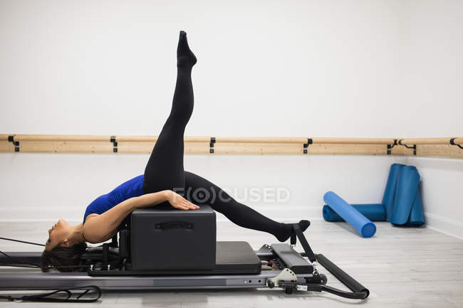 Жінка тренується на обладнанні реформатора в тренажерному залі — стокове фото