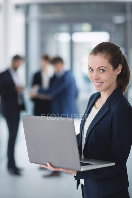 Портрет деловой женщины, стоящей в офисе и использующей ноутбук — стоковое фото