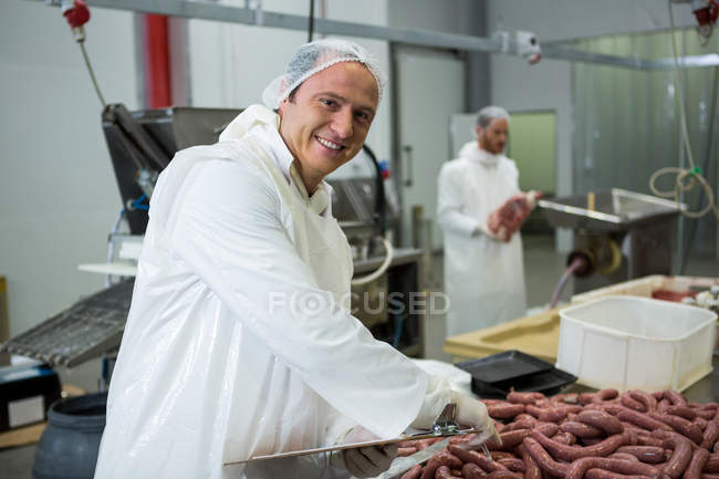 Portrait of male butcher maintaining records on clipboard at meat factory — Stock Photo