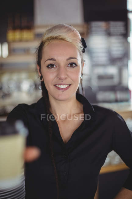 Портрет офіціантки, що стоїть з одноразовою чашкою кави в кафе — стокове фото