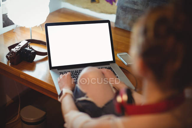 Vue arrière de la femme utilisant un ordinateur portable à la maison — Photo de stock
