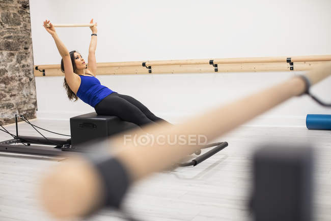 Woman exercising on reformer in fitness studio — Stock Photo