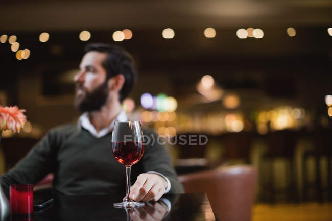 Hombre sentado con copa de vino en el bar - foto de stock