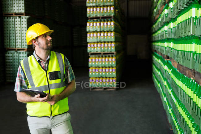 Молодой человек осматривает бутылки на складе — стоковое фото