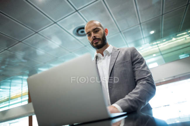 Empresario que usa laptop en la sala de espera en la terminal del aeropuerto - foto de stock