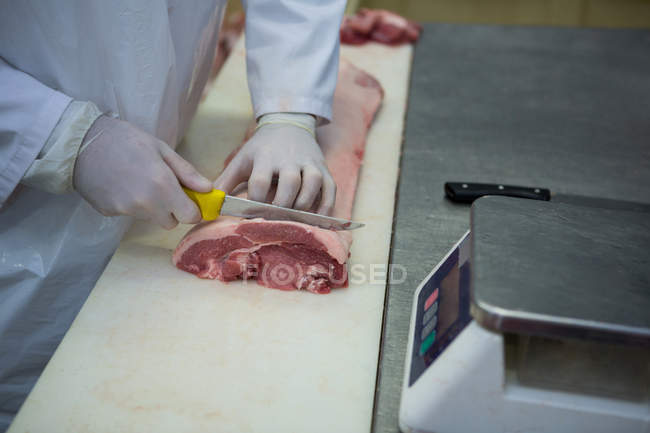 Section médiane du boucher coupant la viande à l'usine de viande — Photo de stock