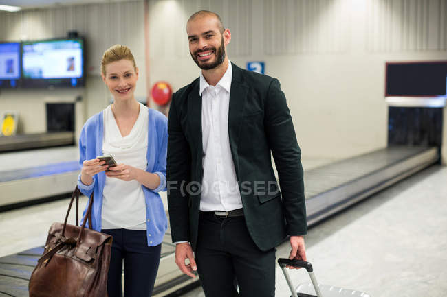 Porträt eines Paares, das mit Gepäck im Wartebereich des Flughafens steht — Stockfoto