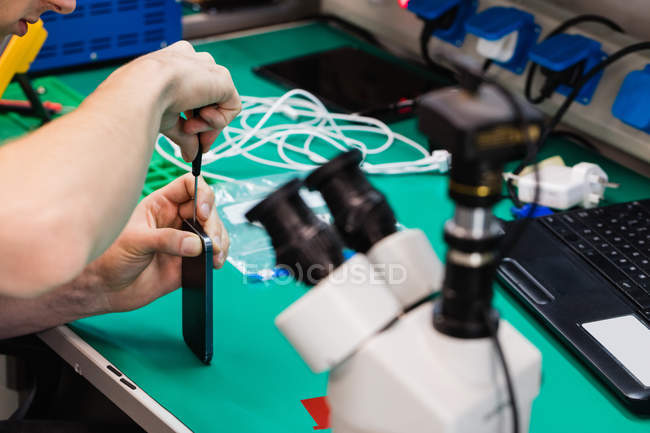 Close-up of man repairing mobile phone in repair centre — Stock Photo