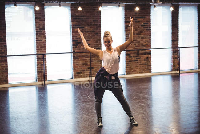 Жінка стоїть зі зброєю, піднятою в балетній студії — стокове фото