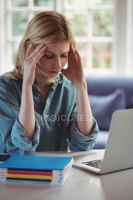 Напружена жінка сидить руками на лобі у вітальні вдома — стокове фото