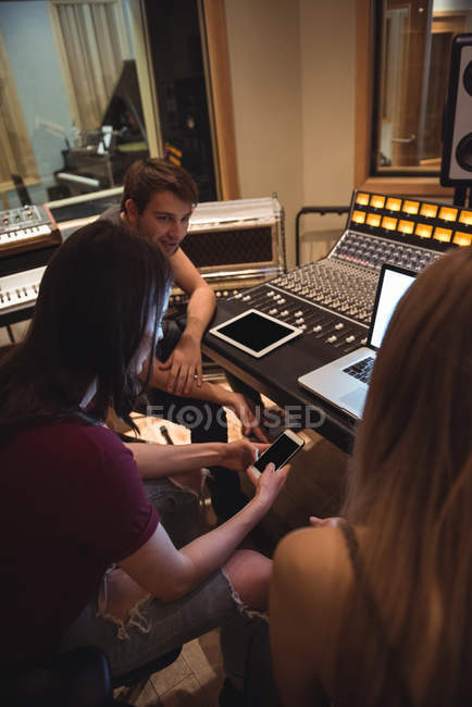 Audio engineers discussing over mobile phone near sound mixer in music studio — Stock Photo