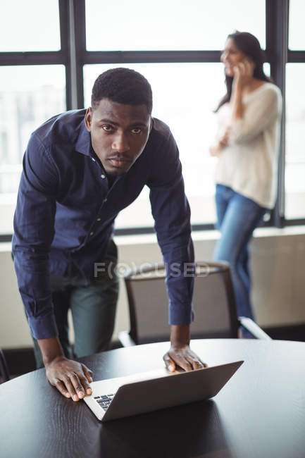 Портрет бизнесмена с ноутбуком на столе в офисе — стоковое фото