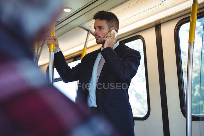 Businessman talking on mobile phone while travelling in train — Stock Photo