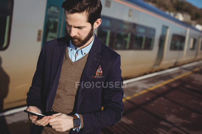 Businessman using mobile phone at railway station — Stock Photo