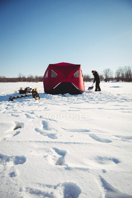 Eisfischer gräbt mit Schaufel in verschneiter Landschaft — Stockfoto