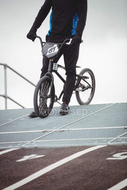 Ciclista in piedi con BMX bike alla rampa di partenza in skatepark — Foto stock