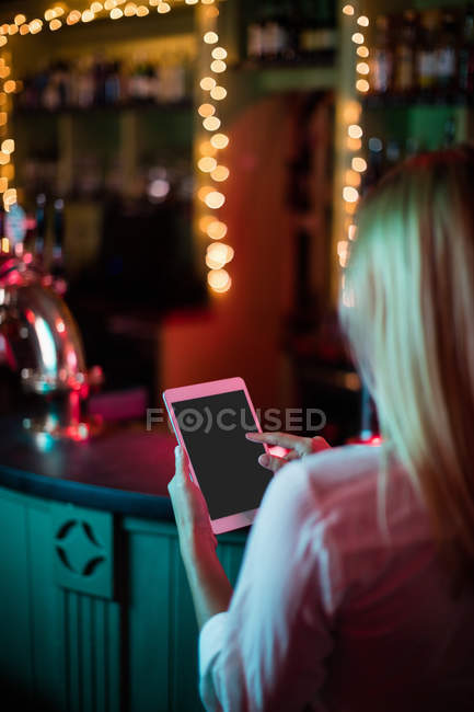 Vue arrière de la serveuse utilisant une tablette numérique dans le bar — Photo de stock