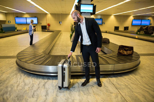 Empresário com saco de carrinho na área de espera no terminal do aeroporto — Fotografia de Stock