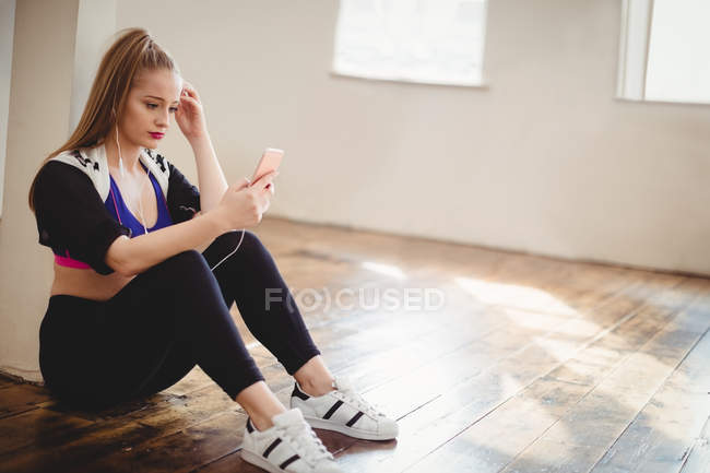 Mulher bonita ouvindo música no celular em estúdio — Fotografia de Stock