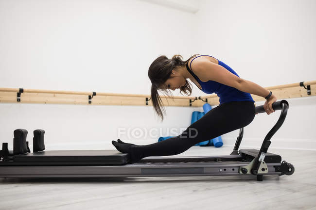 Strong woman exercising on reformer in gym — Stock Photo