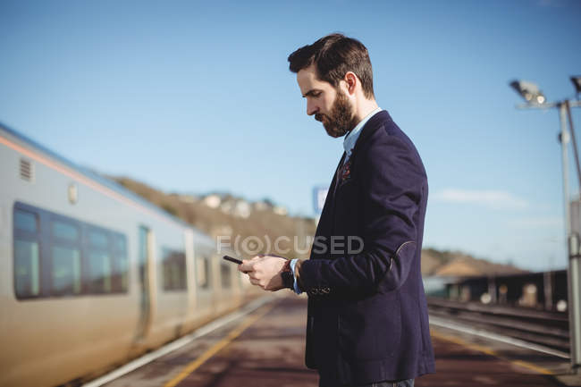 Empresário usando telefone celular na estação ferroviária — Fotografia de Stock