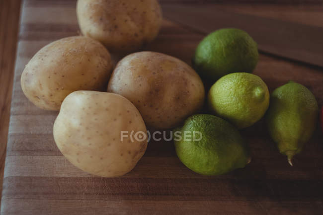 Primer plano de papas frescas y limones en tableta de madera - foto de stock